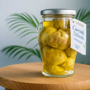 Jar of preserved artichokes with a Collieran label on a wooden surface.