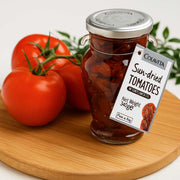 Jar of Colavita sun-dried tomatoes on a wooden board with fresh tomatoes and a label.