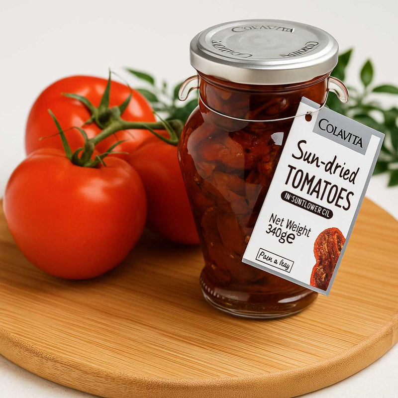 Jar of Colavita sun-dried tomatoes on a wooden board with fresh tomatoes and a label.