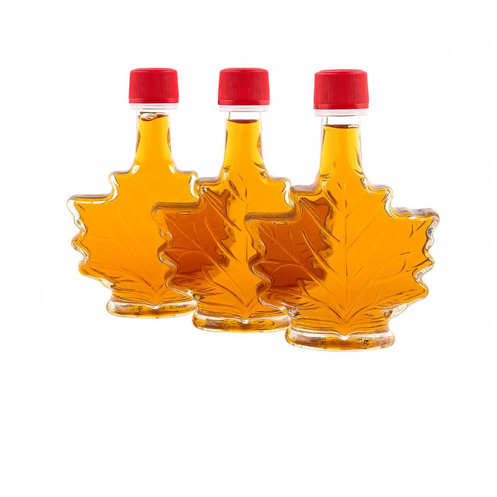 Three maple syrup bottles shaped like leaves with red caps on a white background