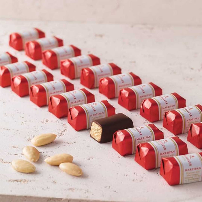 Marzipan candies in red wrappers on a light surface